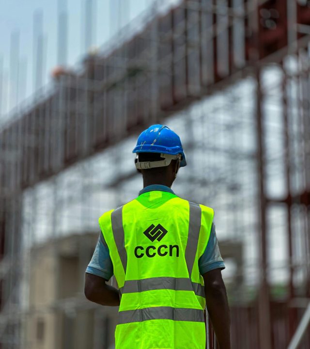 A construction worker in a neon vest and hard hat on a building site, emphasizing safety.